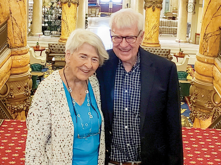 Laura and Harold Greer stand at the top of a carpeted stairwell at the Jefferson Hotel