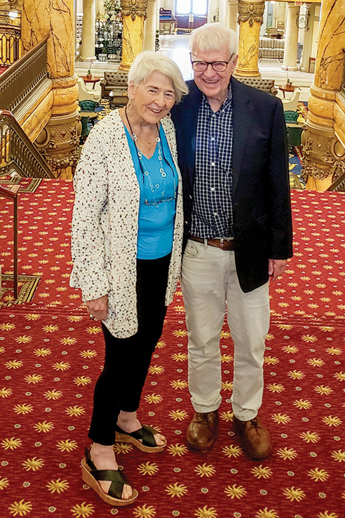 Laura and Harold Greer stand at the top of a carpeted staircase in the Jefferson Hotel