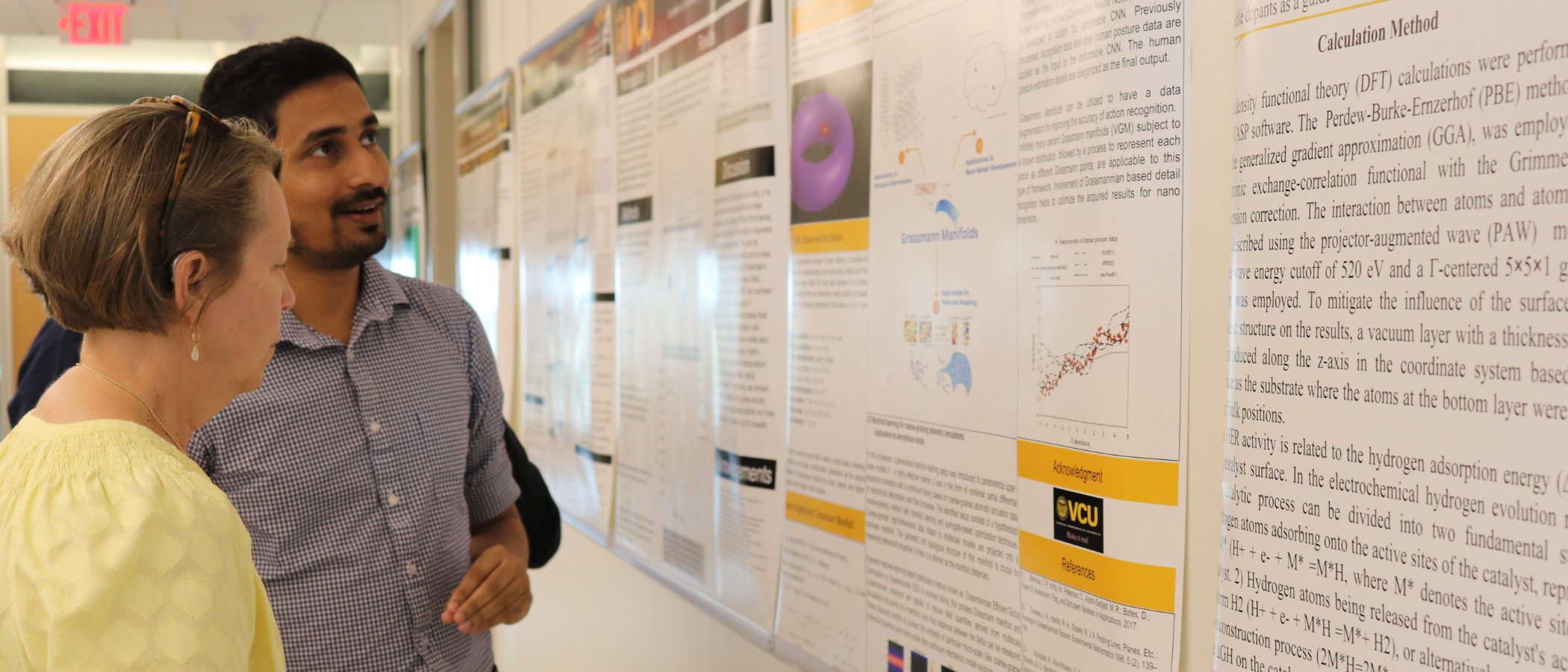 Two people look at research posters on a wall