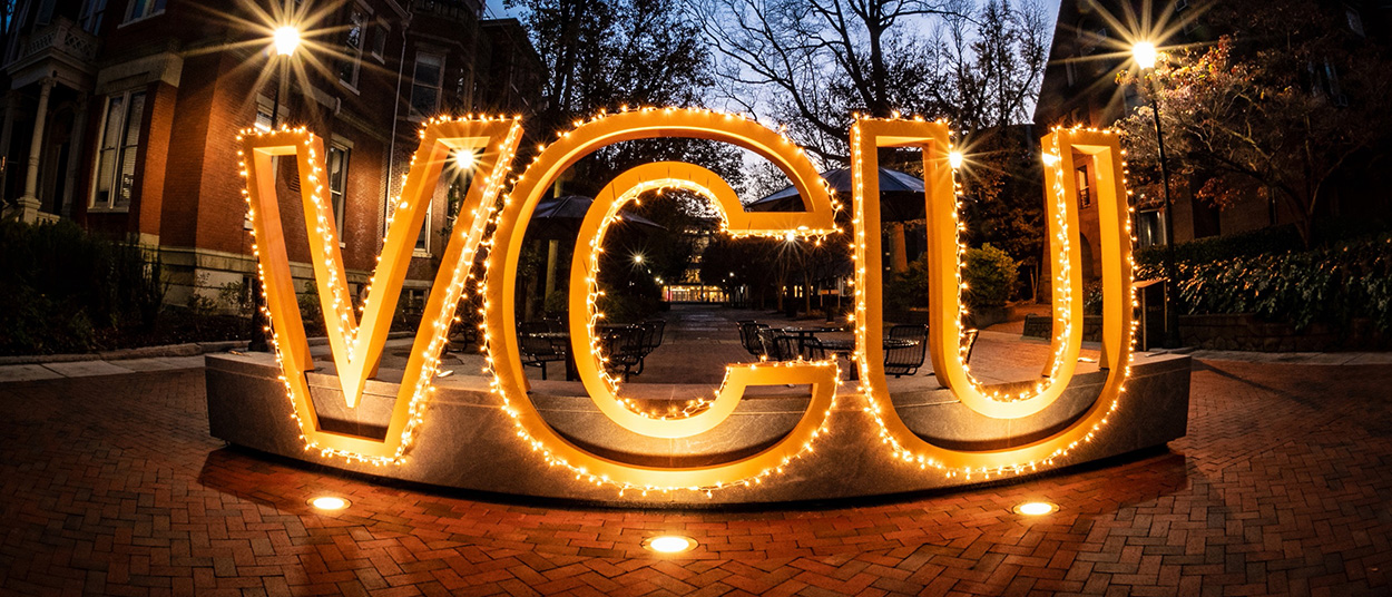 The VCU sign at dusk, outlined in lights